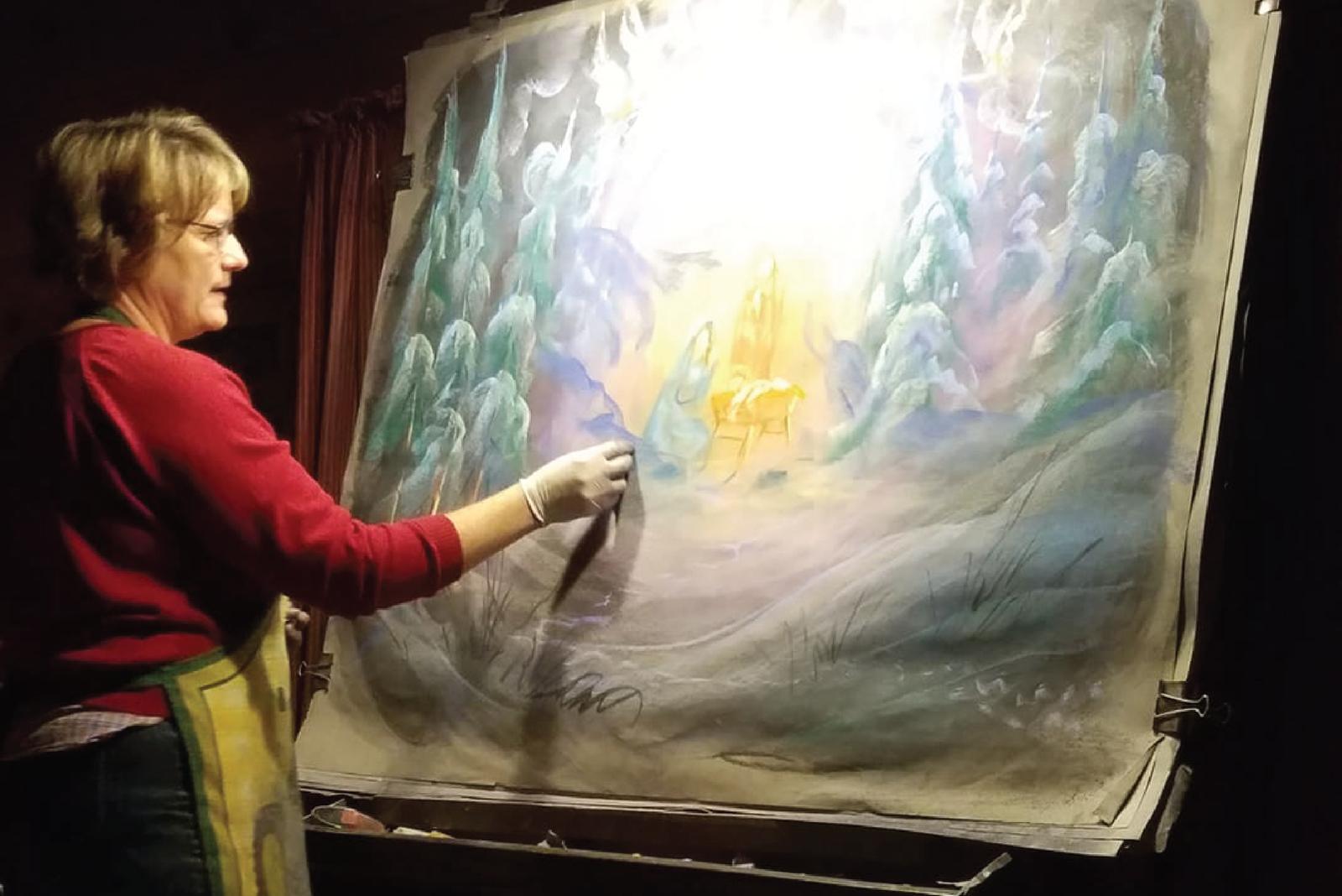 An artist drawing a glowing chalk illustration on a large easel